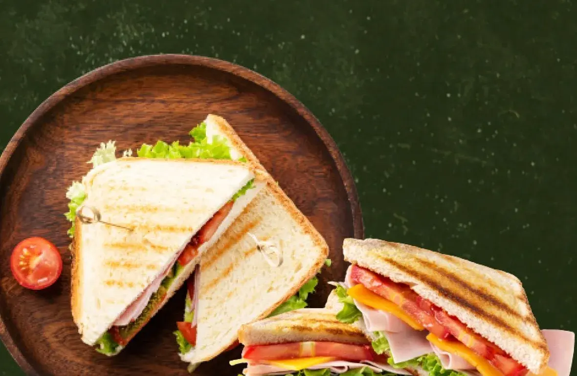 Toasted club sandwiches with lettuce, tomato and cheddar served on a wooden plate at Fit For Life Cafe in Waterloo